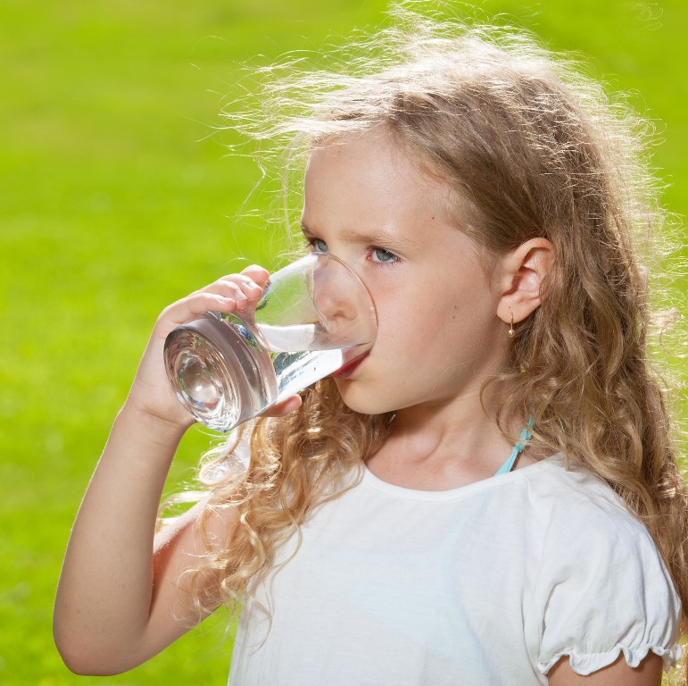 Child drinking water. Girl outdoors